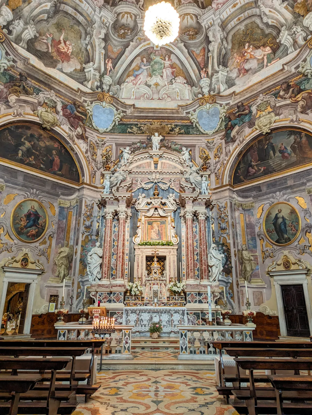 Altarpiece and colourful frescoes at the far end of a church