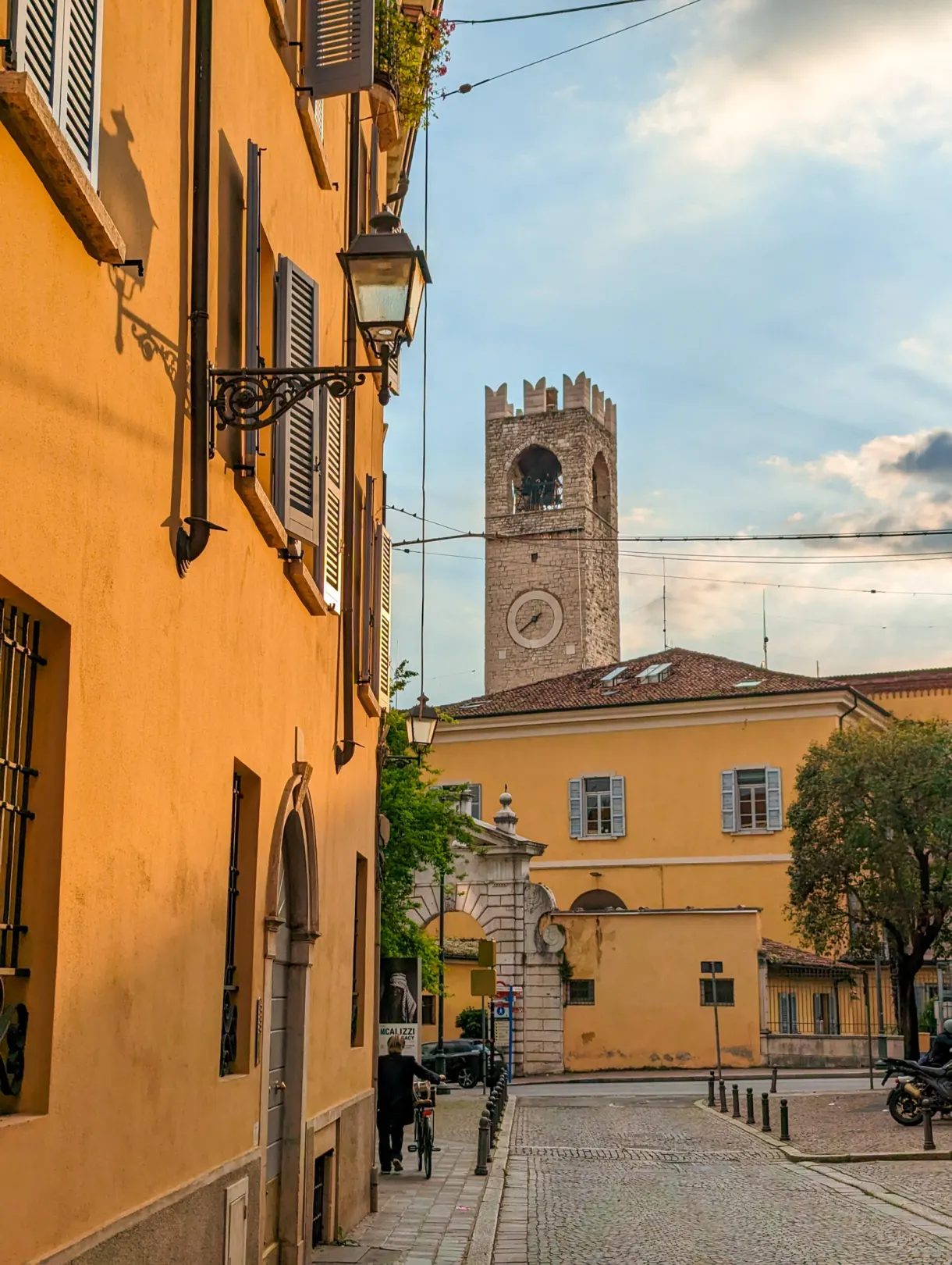 Street with ochre facades closed off by a crenellated tower
