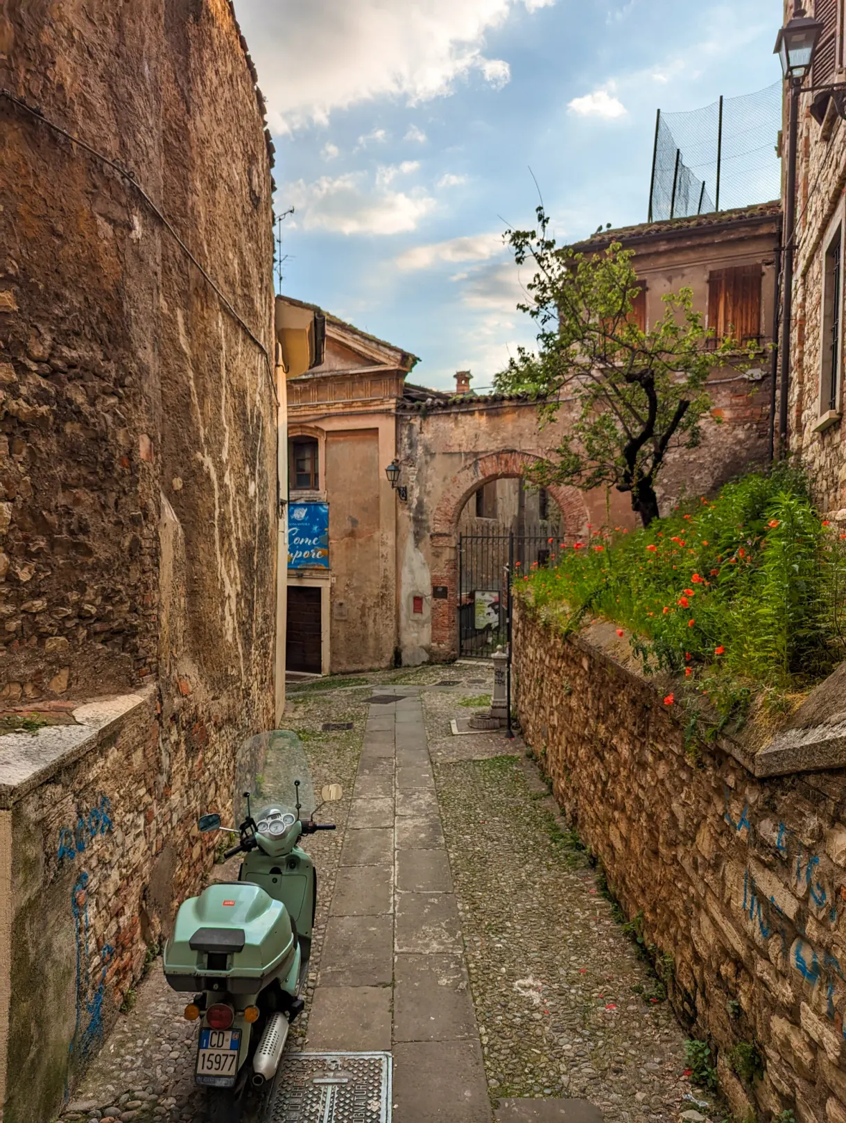 Green scooter parked in a sloping cobbled lane