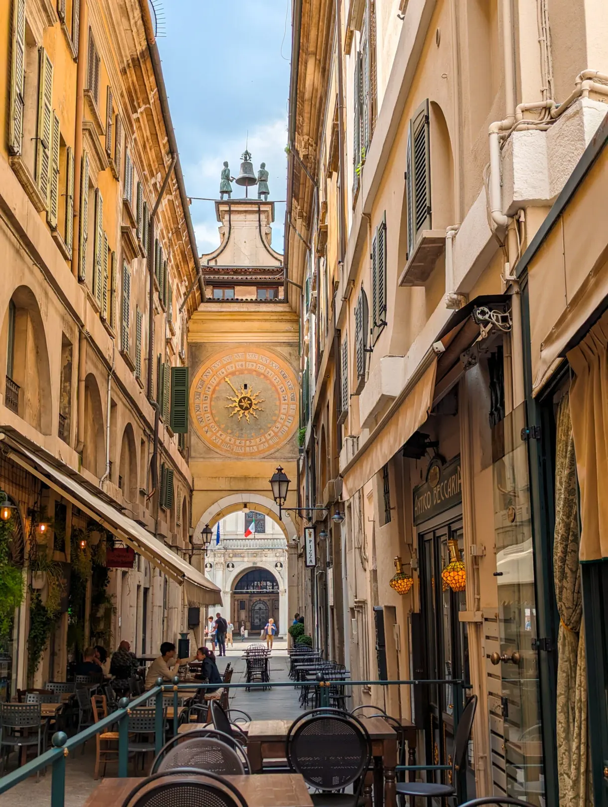 Astronomical clock glimpsed at the end of a lane with terraces