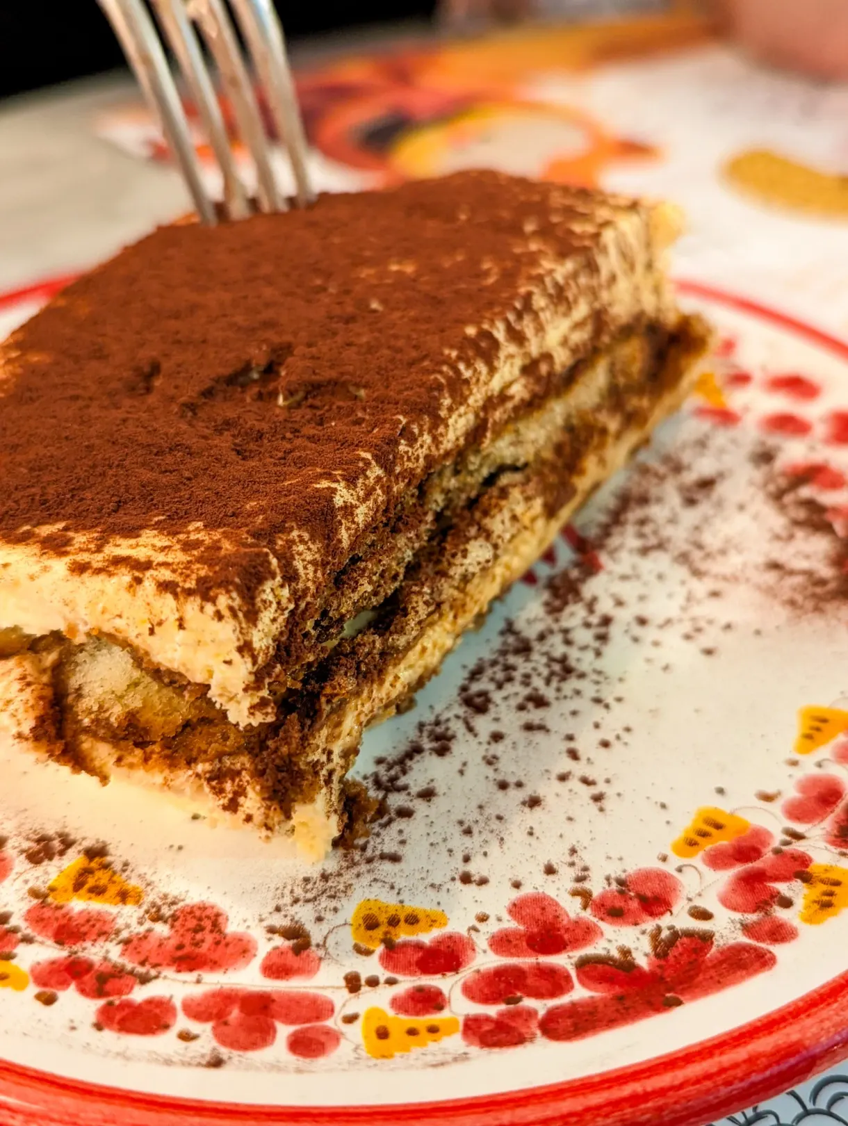 Slice of tiramisu dusted with cocoa on a decorated plate
