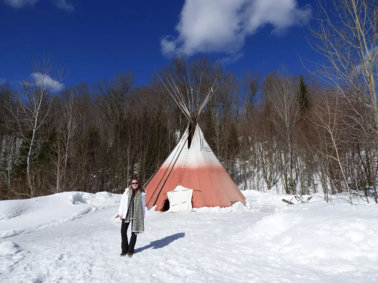 Visiteuse devant un tipi rouge et blanc planté dans la neige