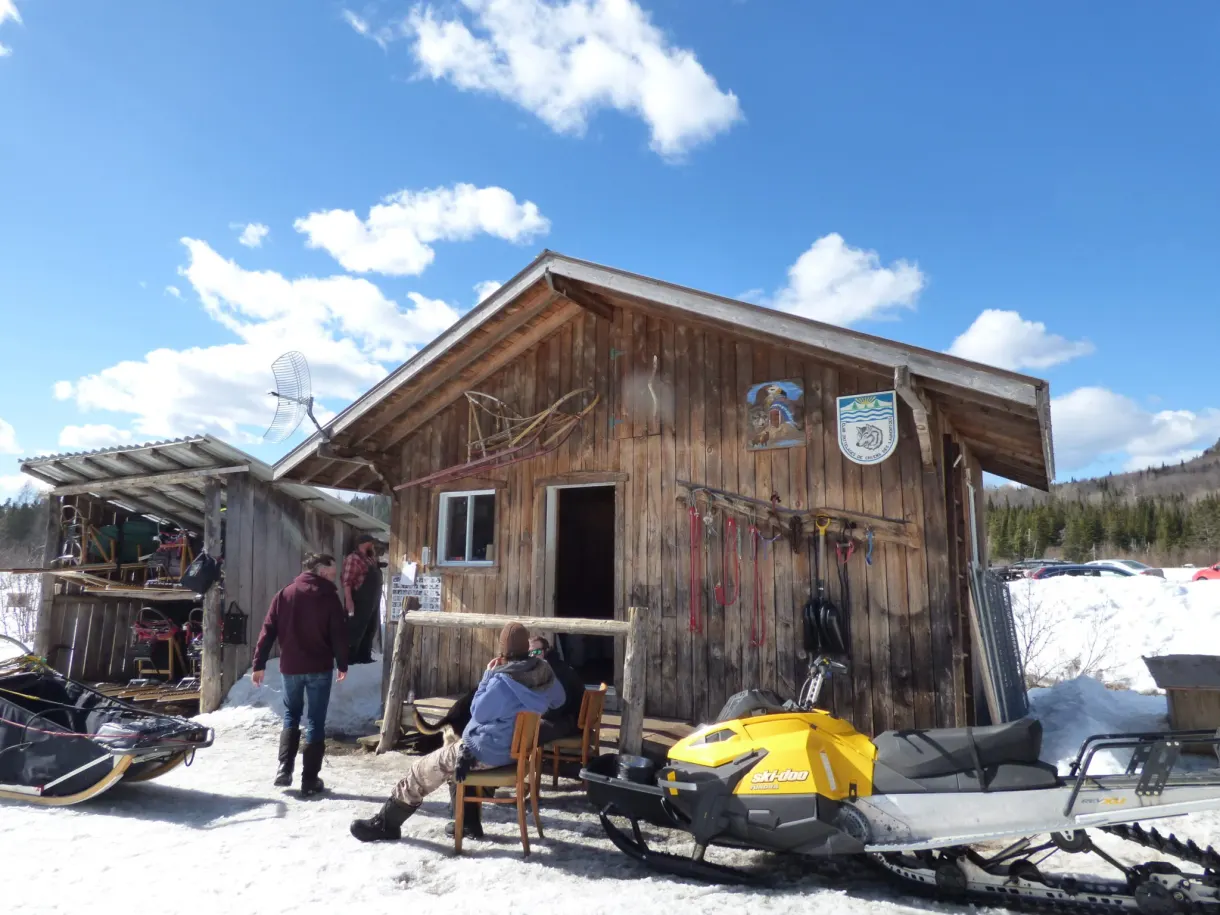 Motoneige jaune et matériel devant la cabane du chenil