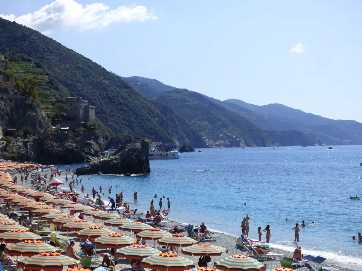 Parasols orange serrés sur les galets, baigneurs dans l'eau