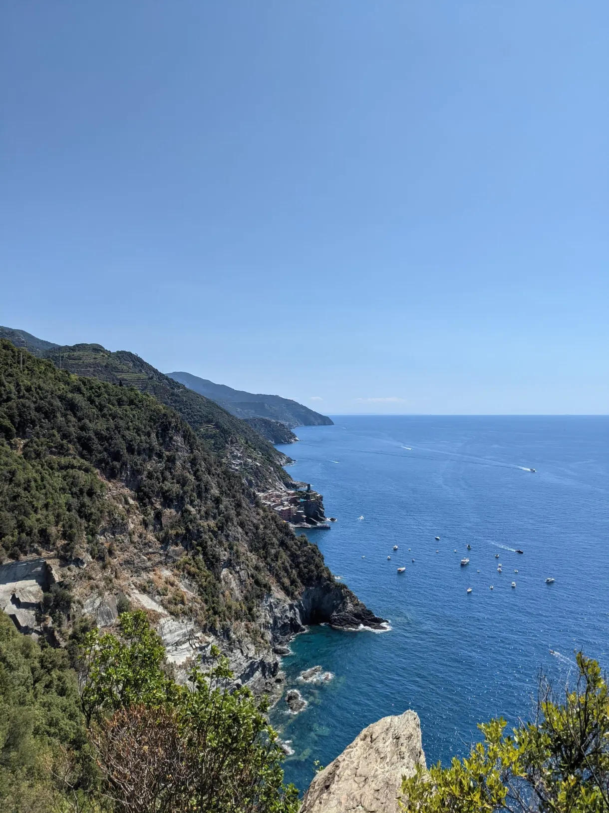 Falaise verte plongeant dans la mer, bateaux au mouillage