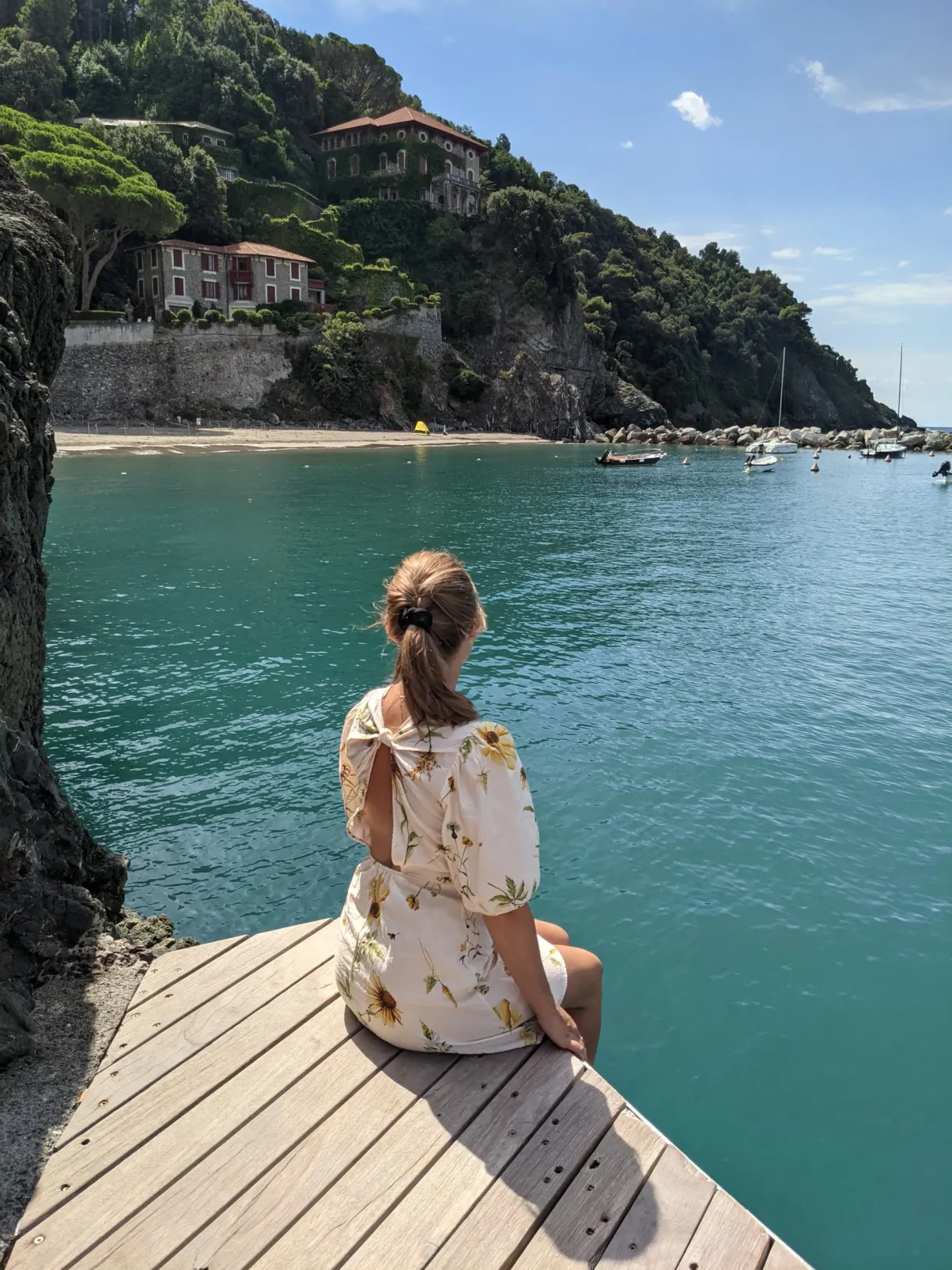 Femme assise au bout d'un ponton de bois, eau turquoise