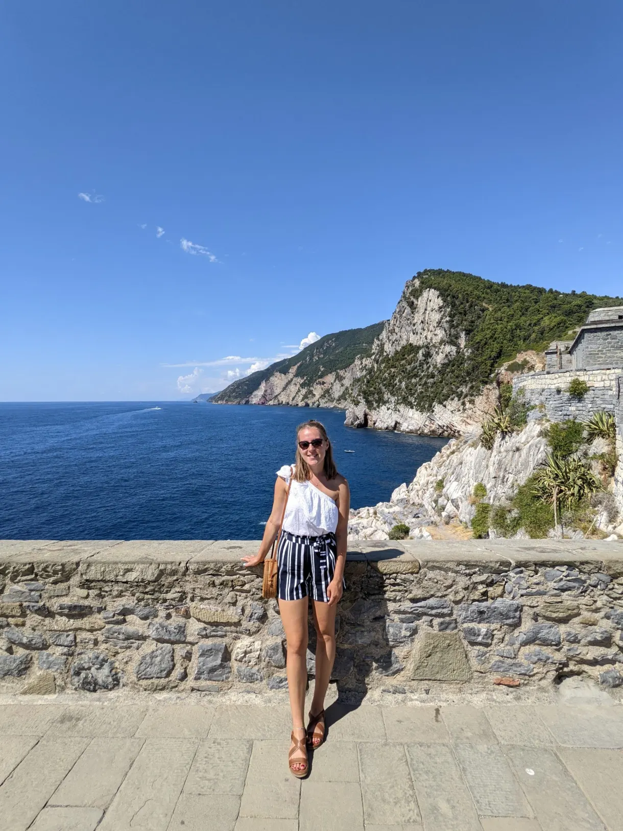 Femme sur une terrasse murée face au cap rocheux