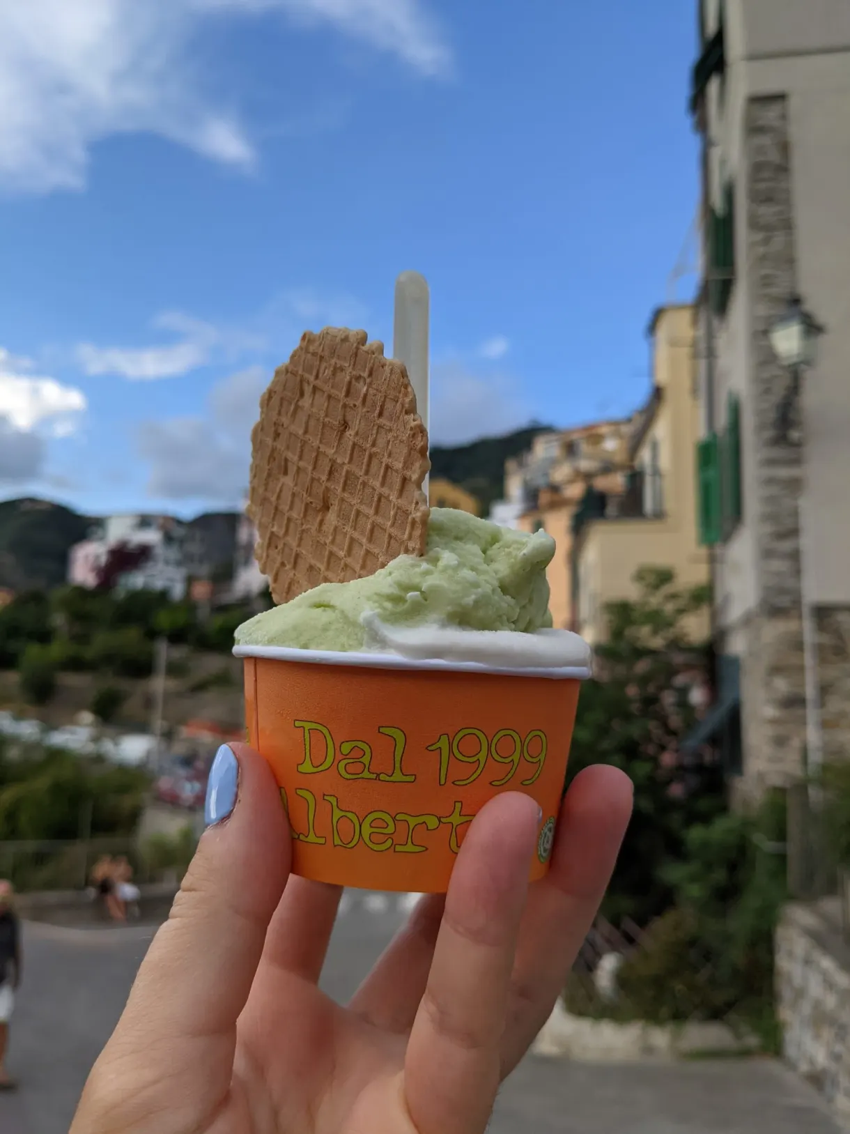 Glace pistache et sa gaufrette tenue face au village