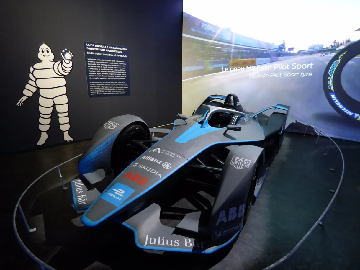 Formula E single-seater on show near a drawing of Bibendum