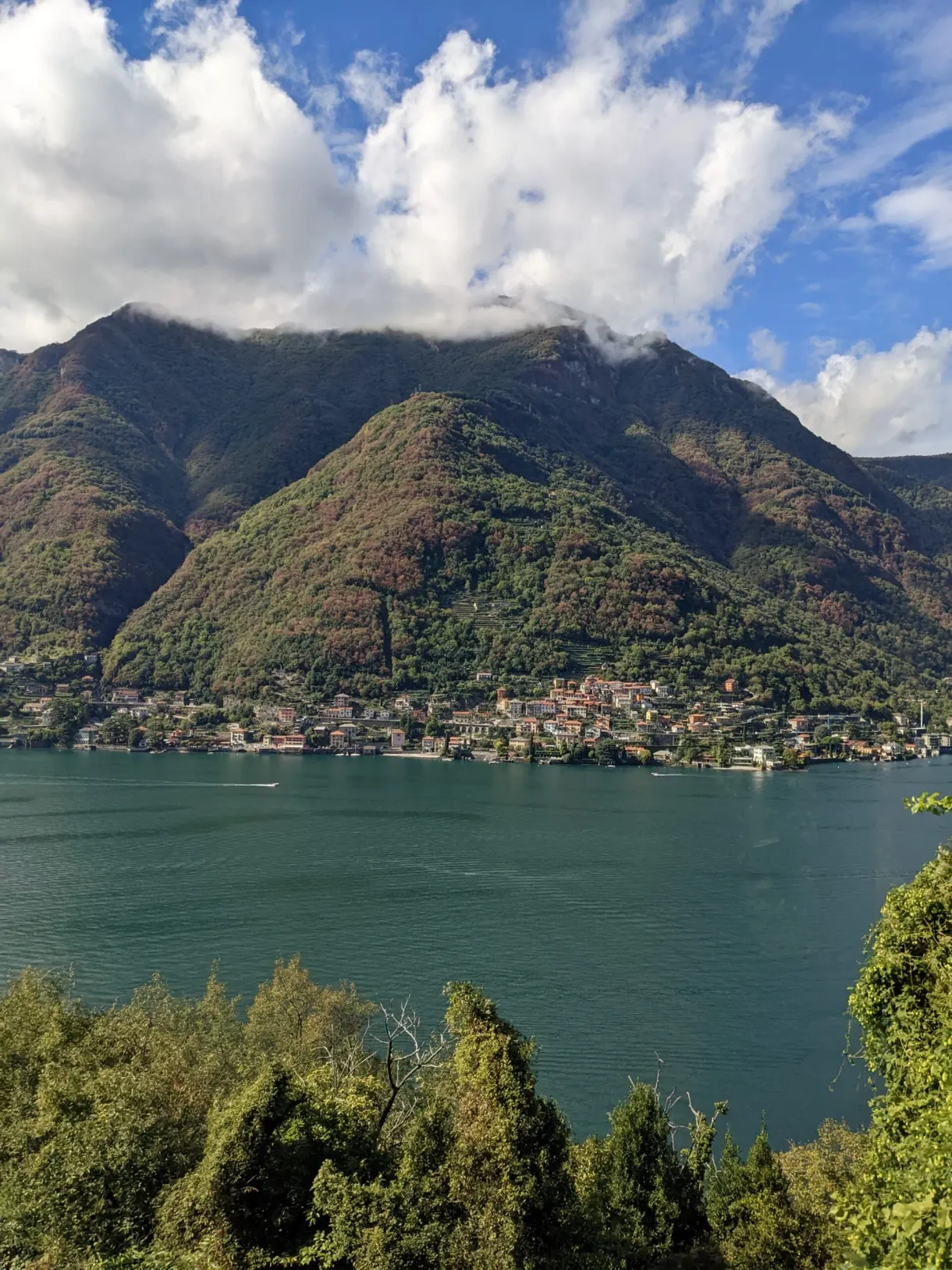 Montagne verte plongeant dans l'eau au-dessus d'un village