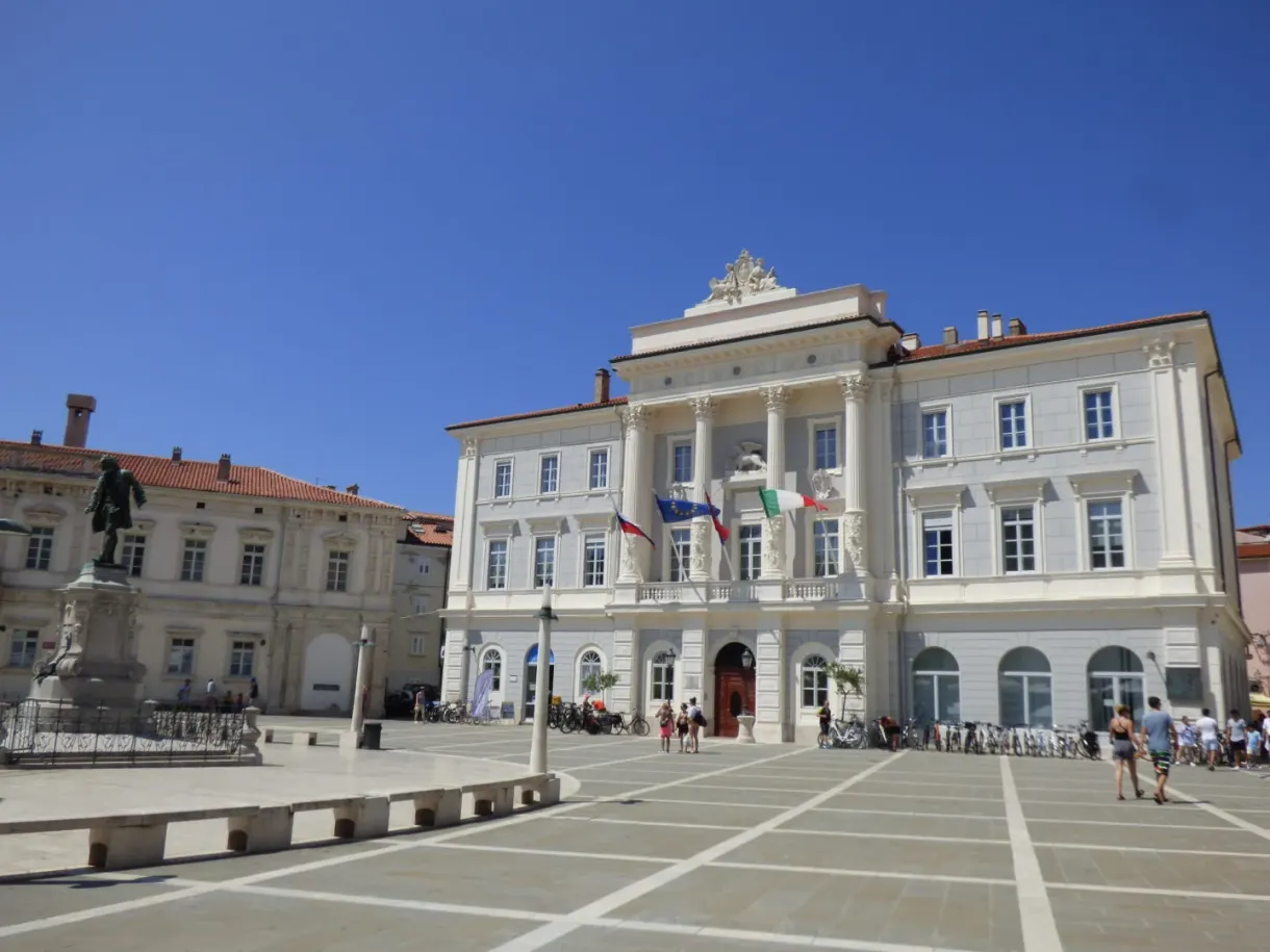 White town hall and statue of the violinist, flags in the wind
