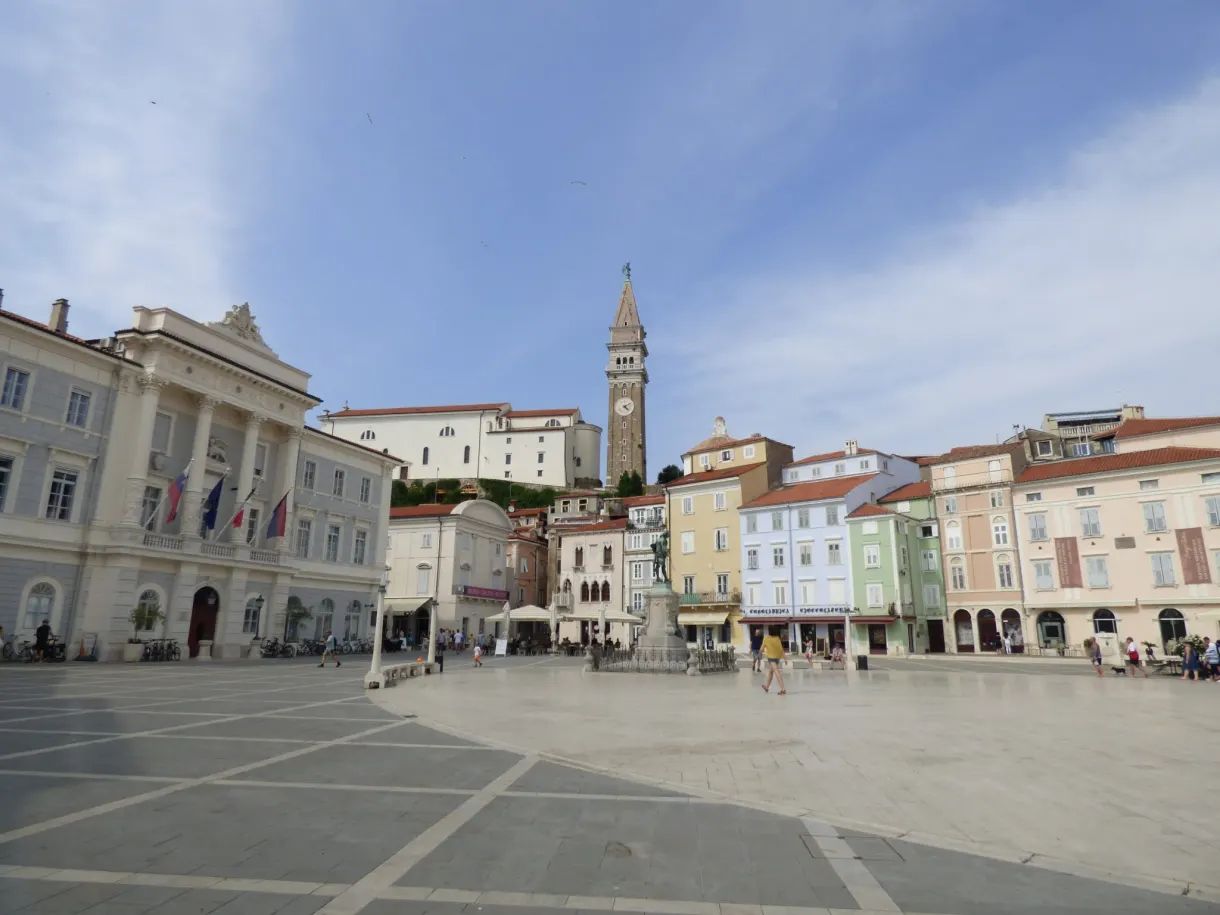 Vast oval square with pale paving, lined with colourful facades