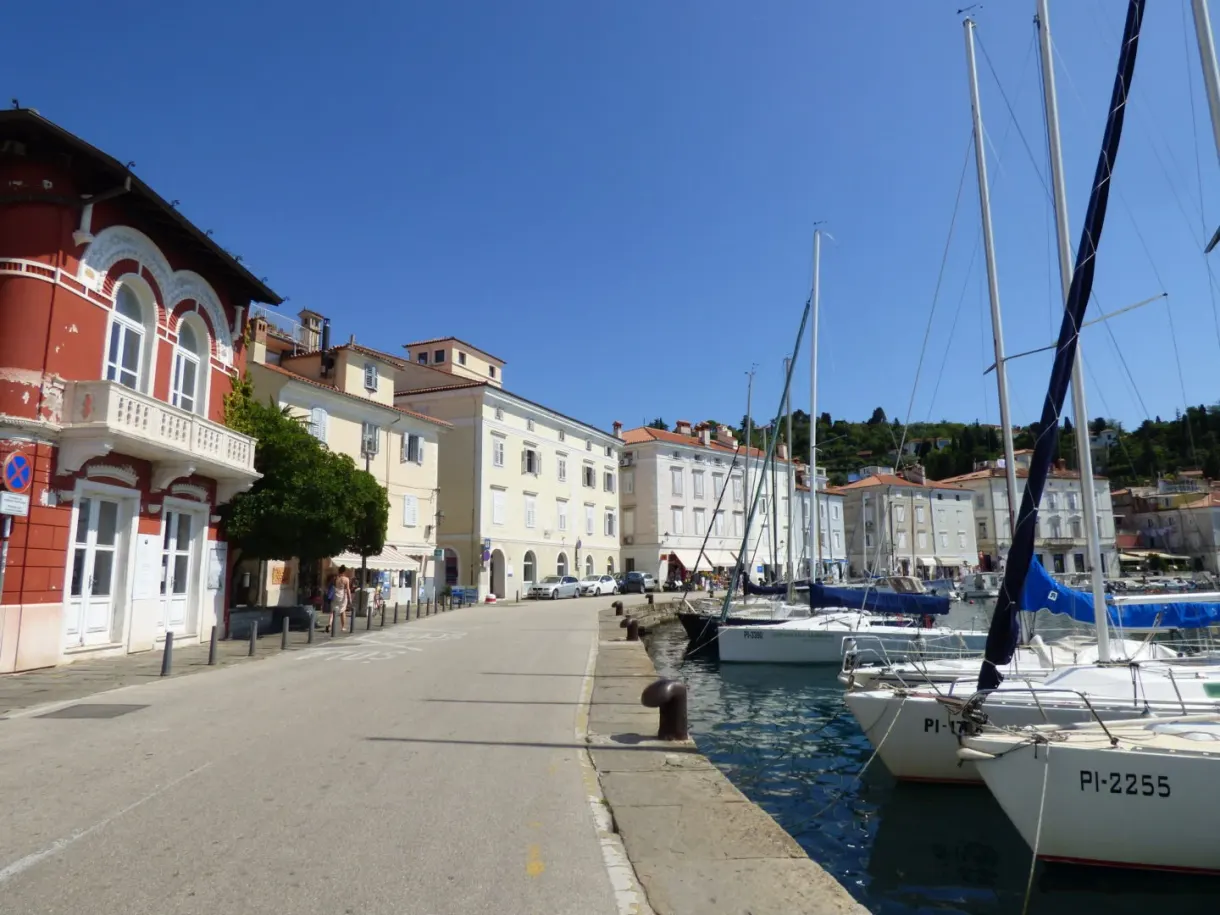 Harbour quay lined with sailing boats, bright red corner house