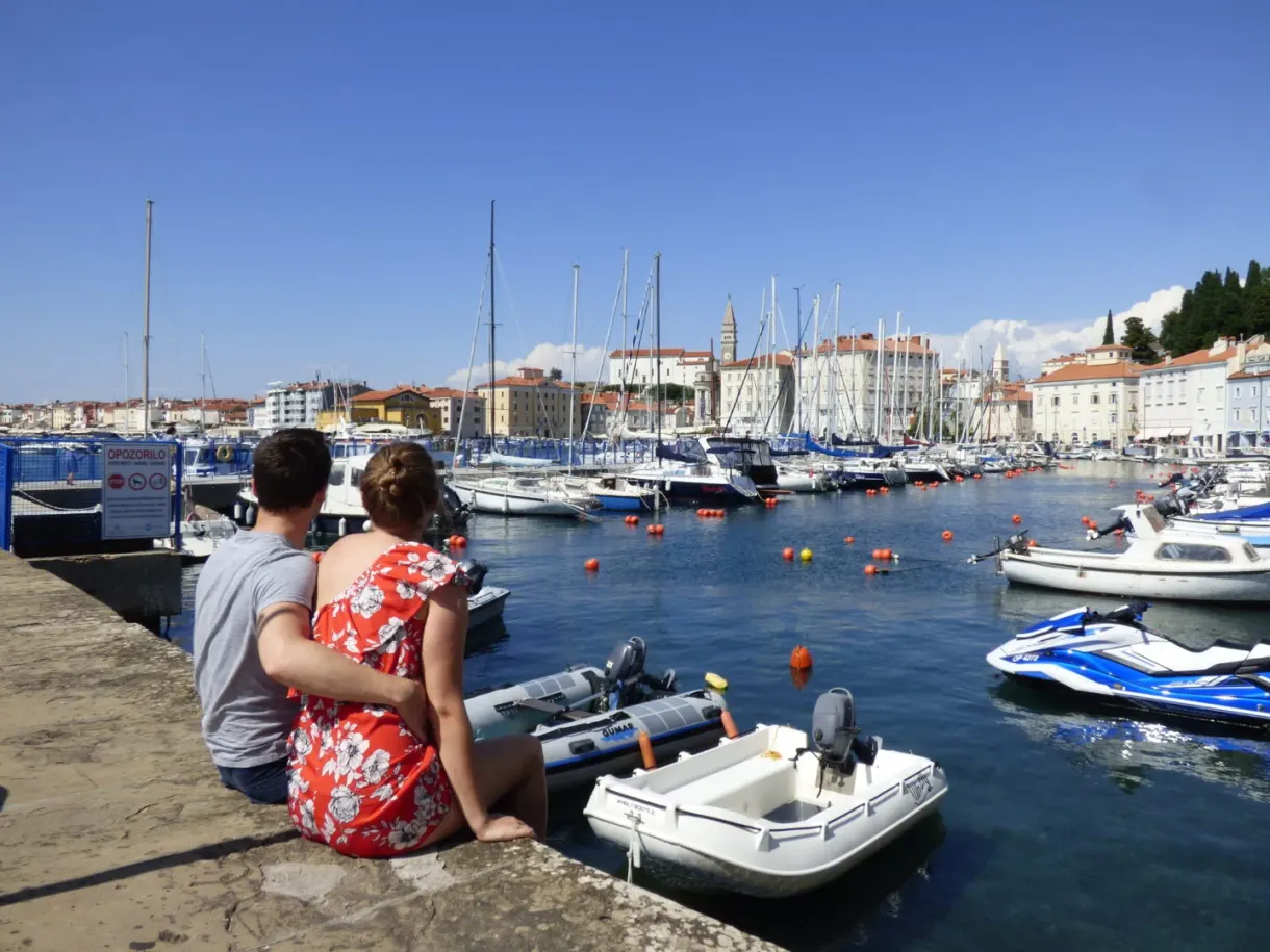 Couple sitting on the low wall facing the boats in the harbour