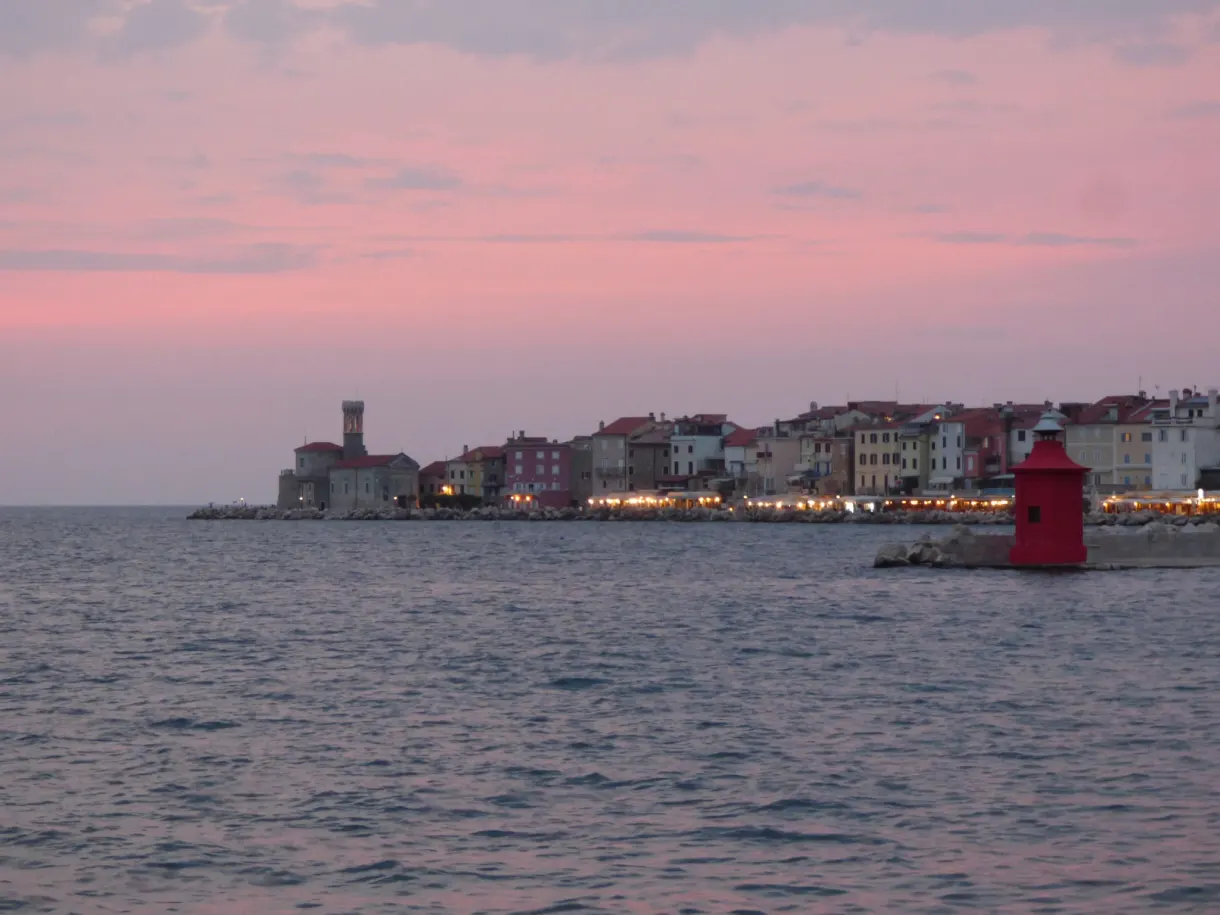 Red lighthouse and silhouette of the old town in the evening