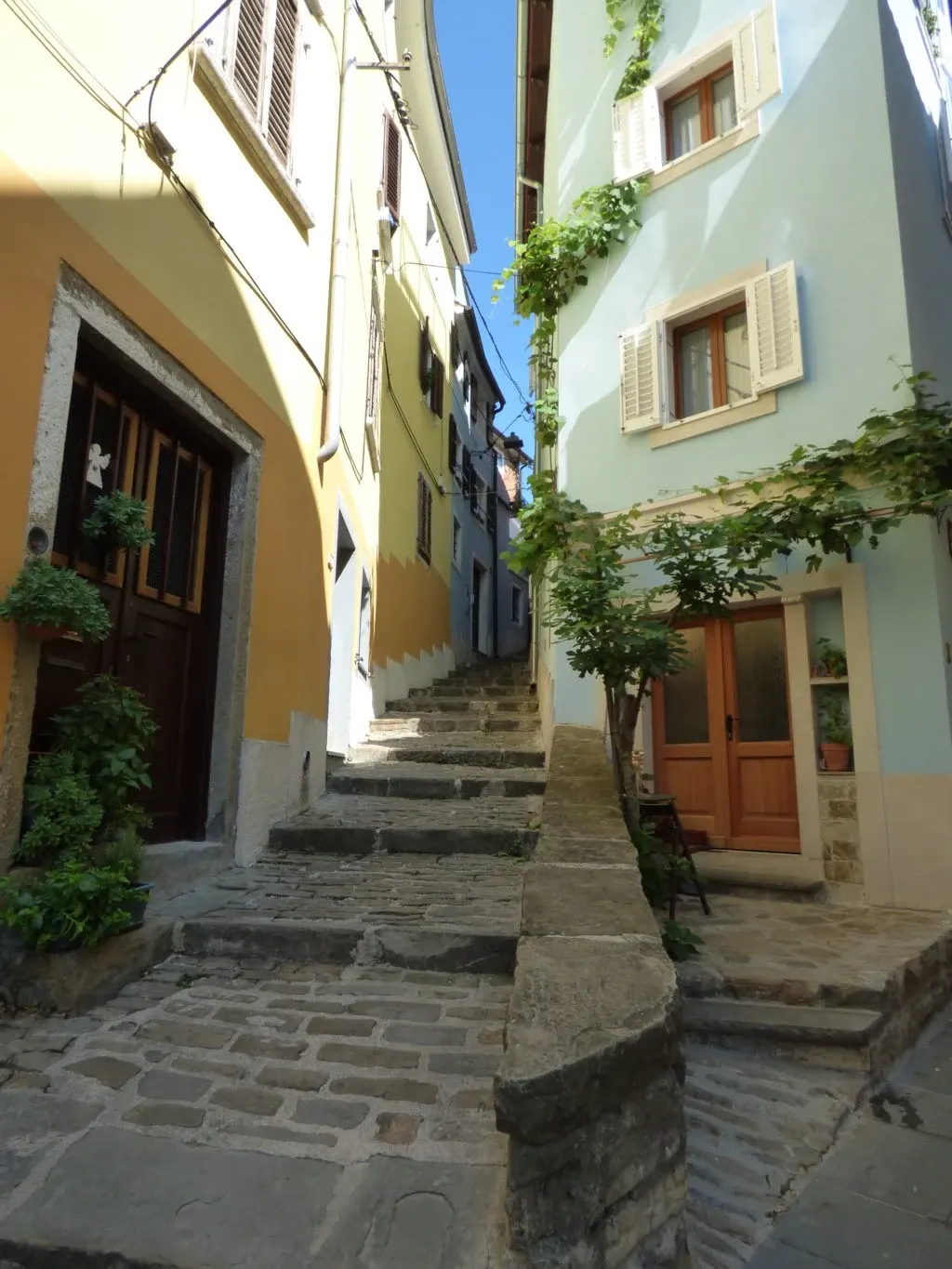 Stone staircase climbing between two houses, green and yellow