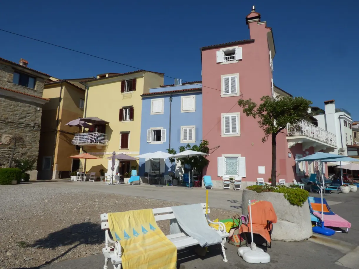 Pink house and deckchairs on a small square by the water