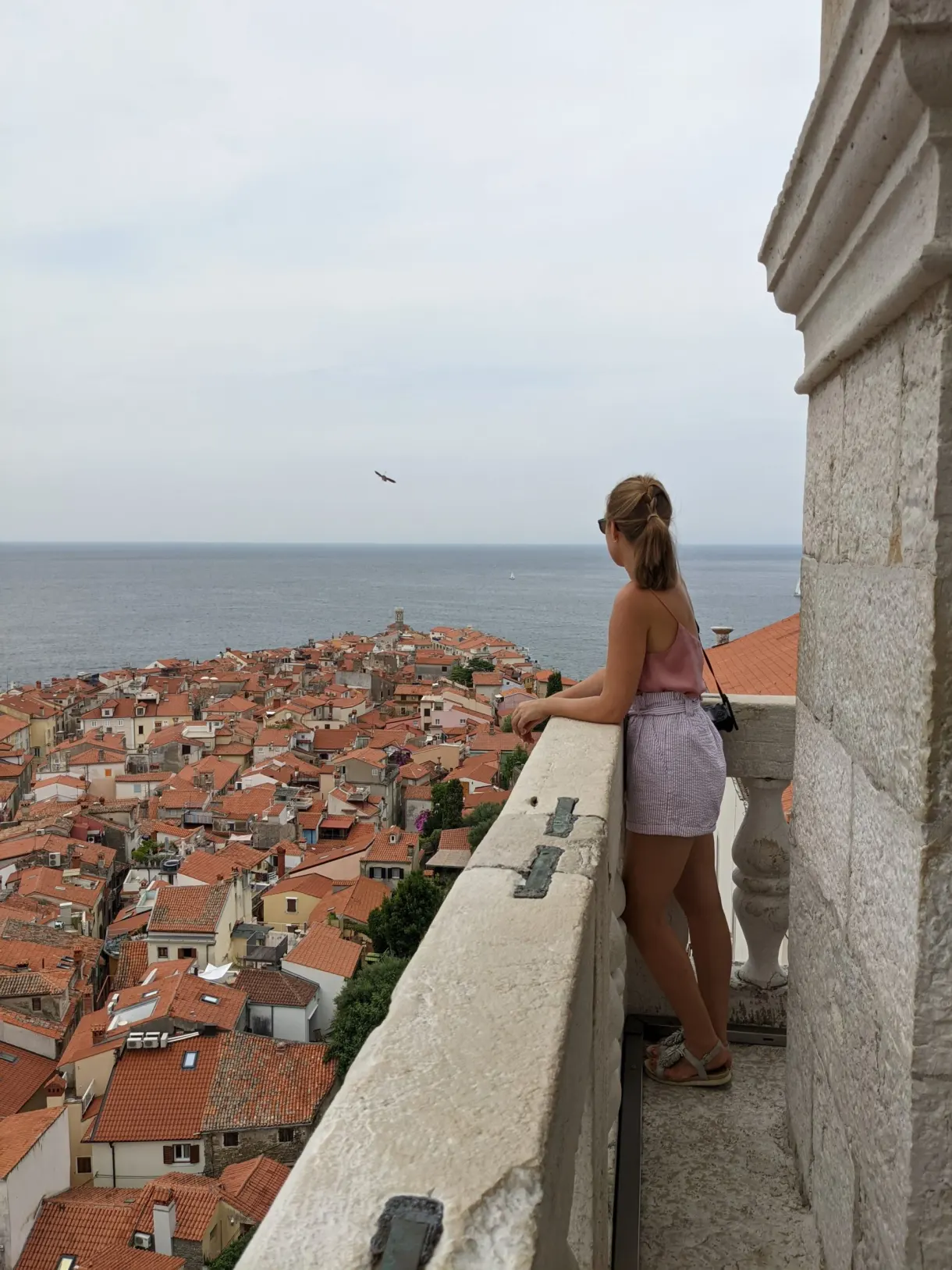 Young woman leaning on the parapet above the tiled roofs