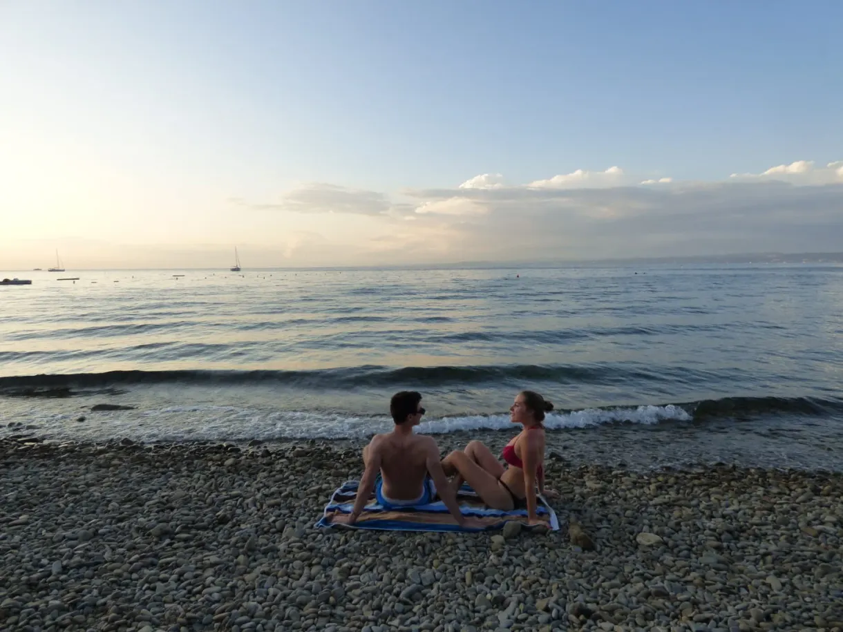 Two bathers sitting on the pebbles at sunset