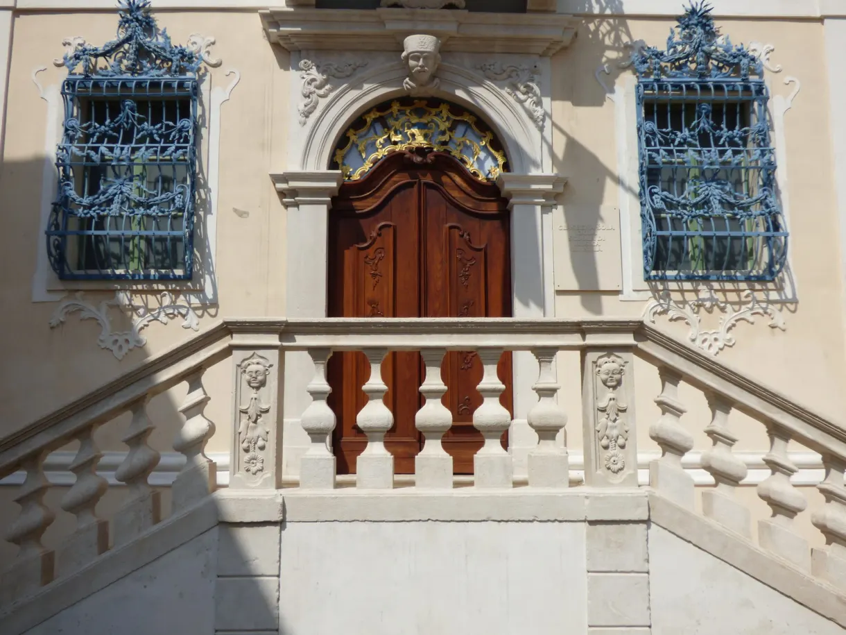 Baroque gateway with a balustrade framed by sky blue railings