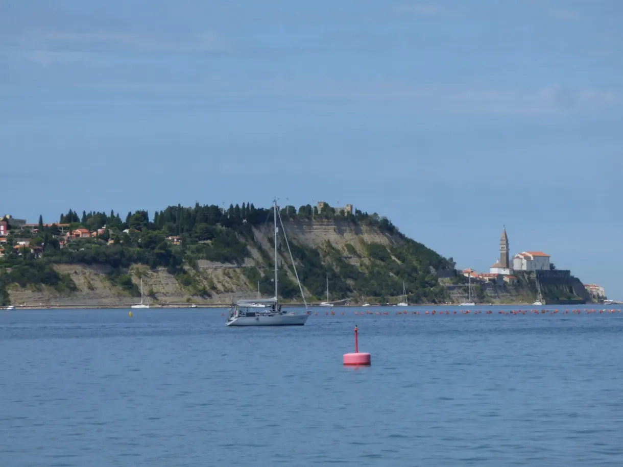 Sailing boat at anchor in front of the peninsula and its bell tower