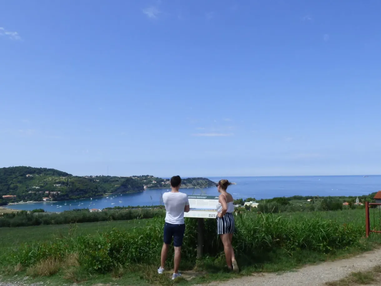 Couple reading a trail sign facing the bay