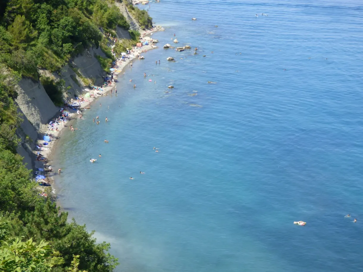 Pebble beach at the foot of the cliff, crystal clear water