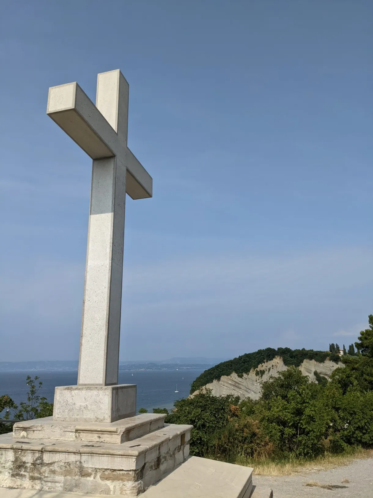 Large white cross standing on a base facing the sea