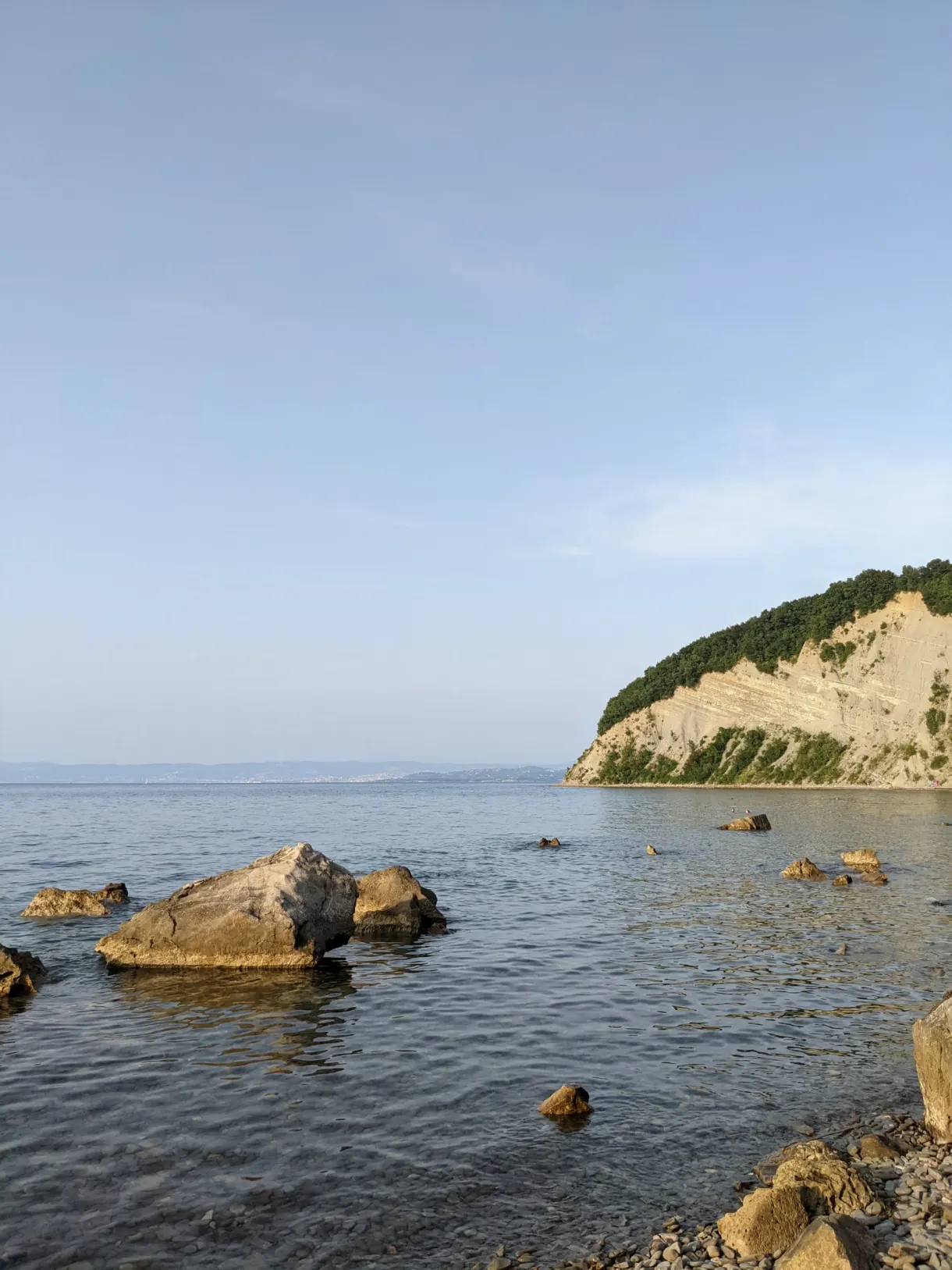 Rocks emerging in front of the pale cliff face