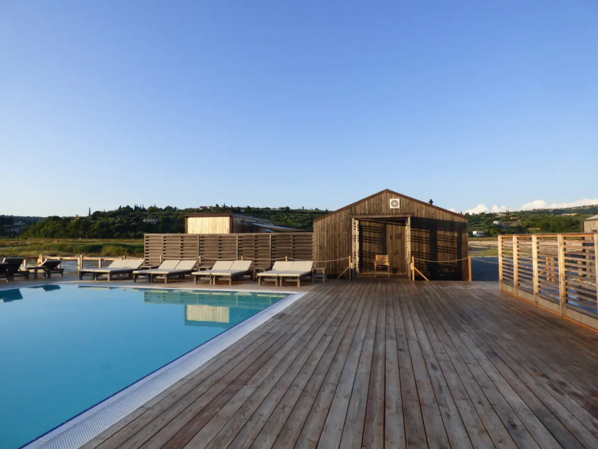 Pool lined with deckchairs in front of a rough wooden cabin