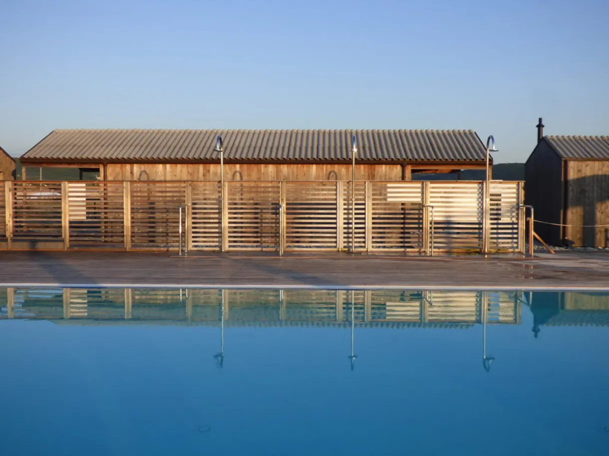 Long mirror pool running in front of the wooden cabins