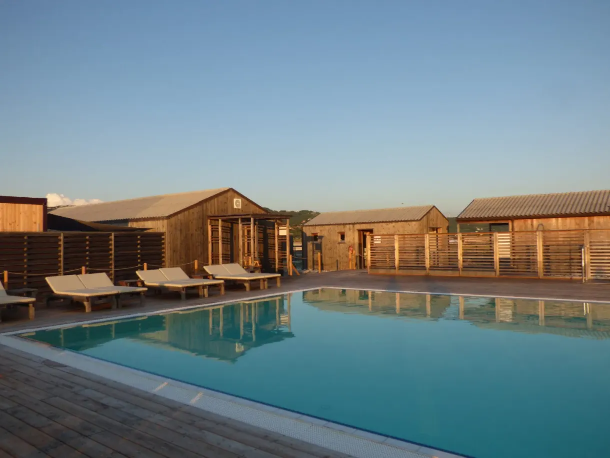 Deckchairs lined up between the cabins and the turquoise pool
