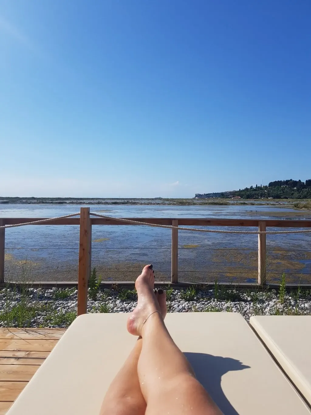 Legs stretched out on a deckchair facing the salt marshes