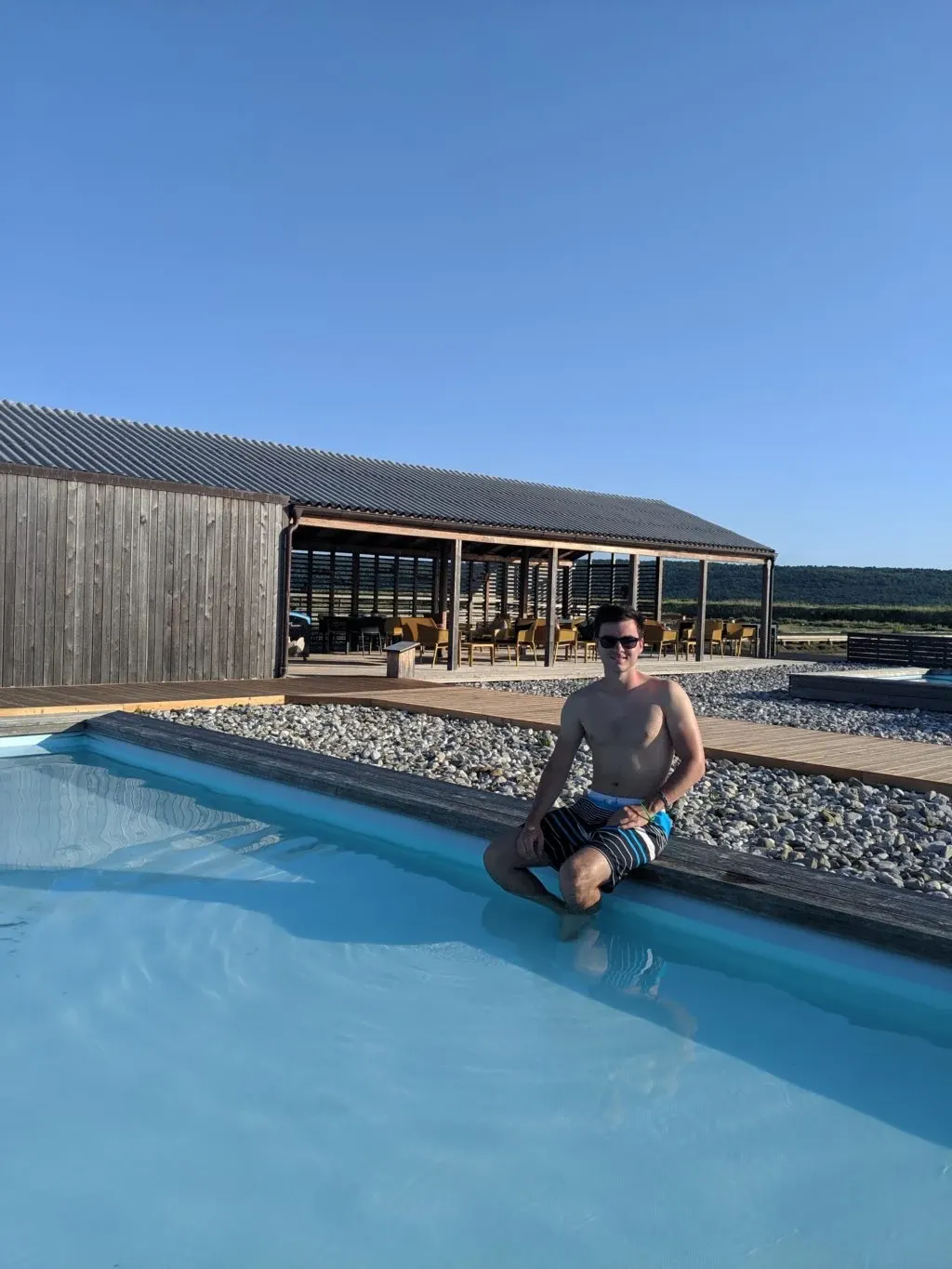 Bather sitting on the edge of the pool in front of the pavilion