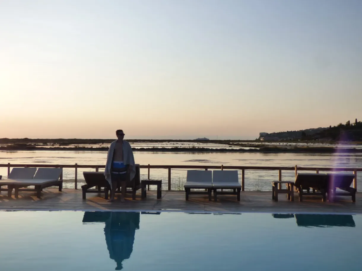 Silhouette standing at the edge of the pool facing the setting sun