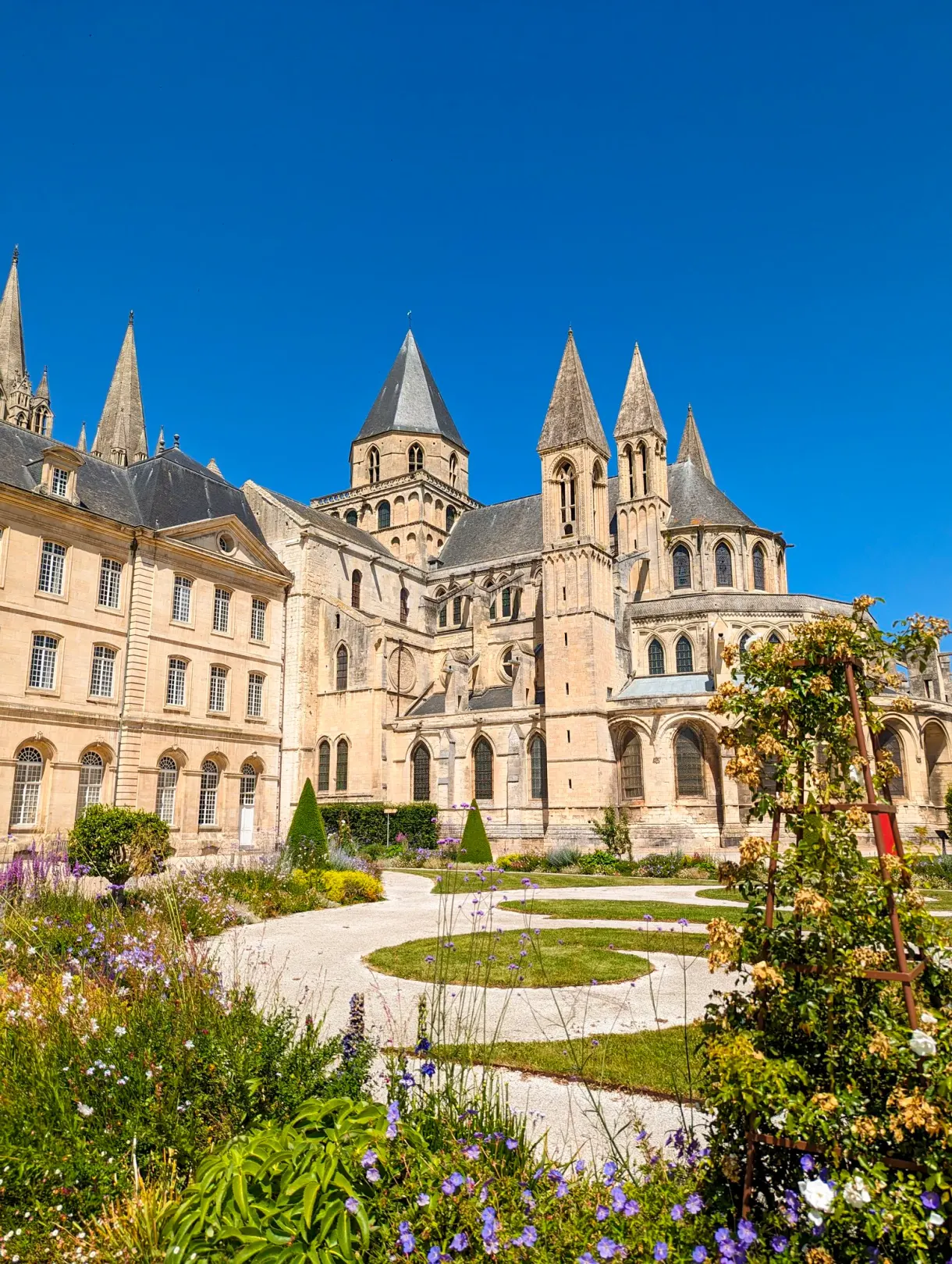 Abbaye aux Hommes and its flower garden under a summer sky