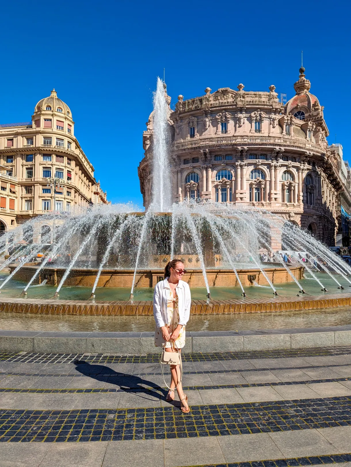 Woman in a light dress in front of the large fountain of the central square