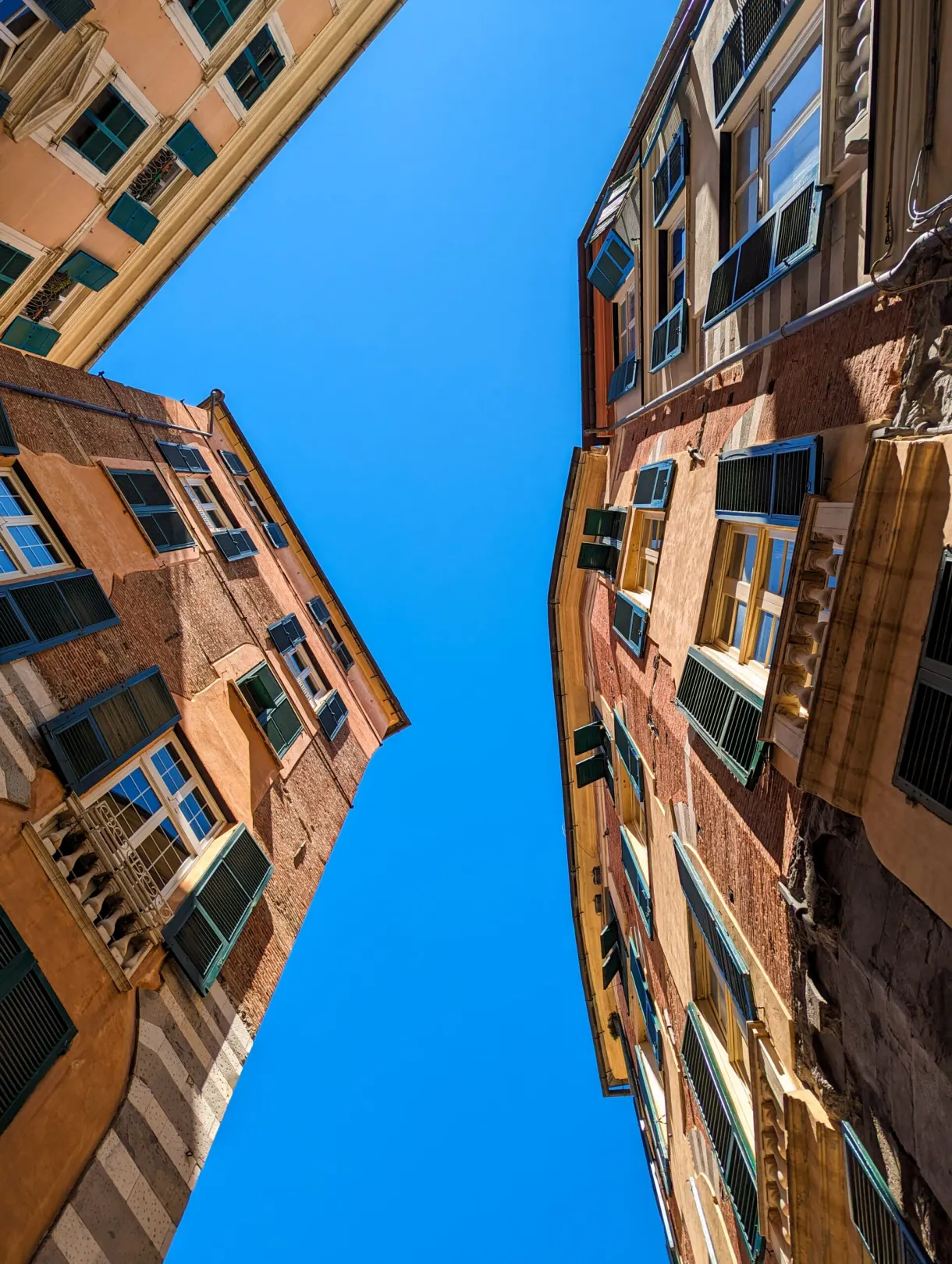 Low angle view between two tall old buildings towards the blue sky