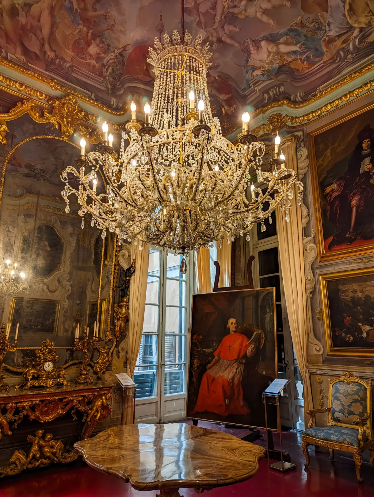 State drawing room with a crystal chandelier and a portrait of a cardinal