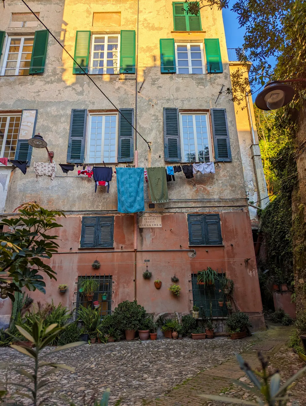 Washing hung at the windows of a facade with green shutters
