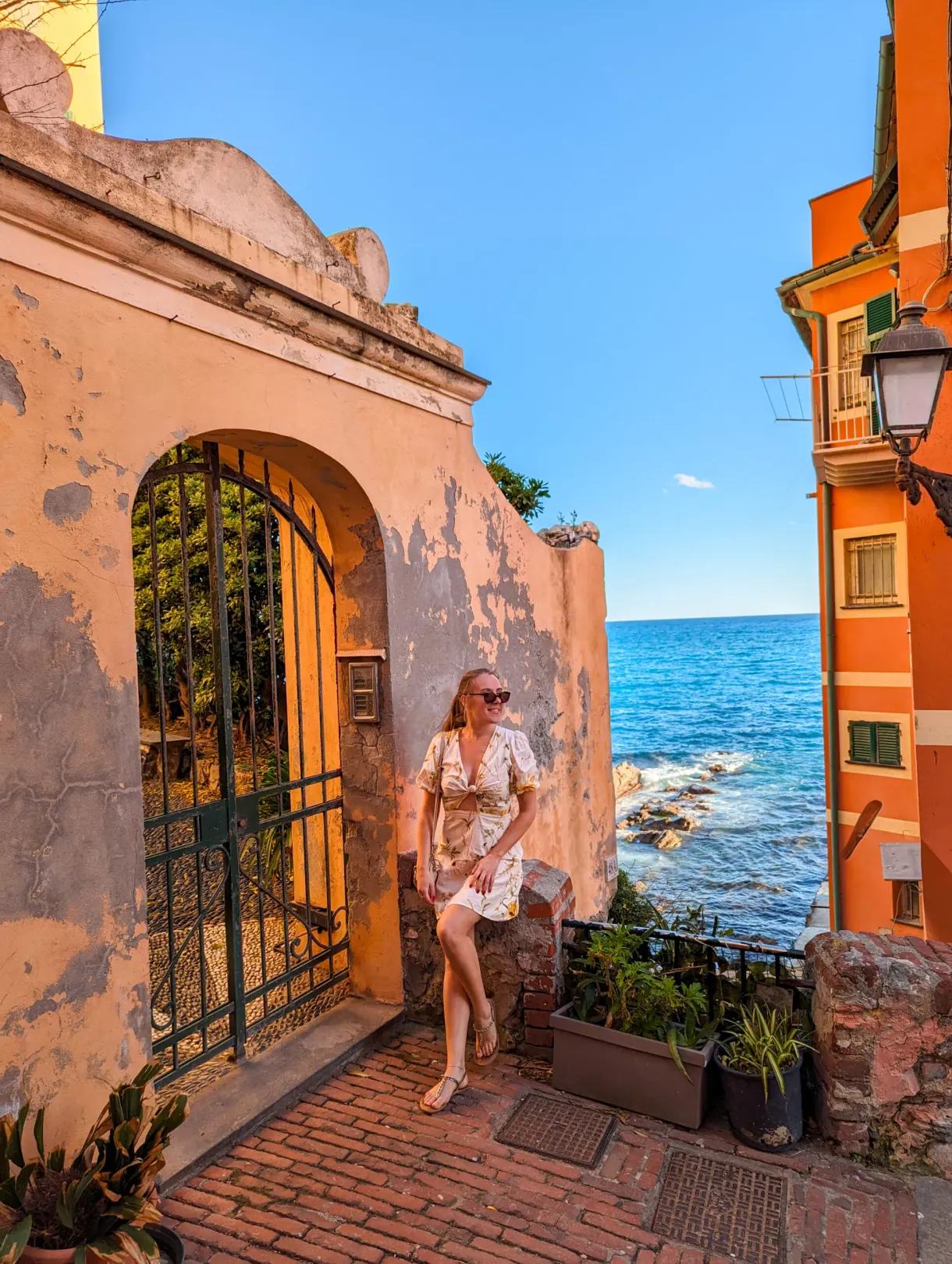 Woman under an old porch opening onto the sea and the orange houses