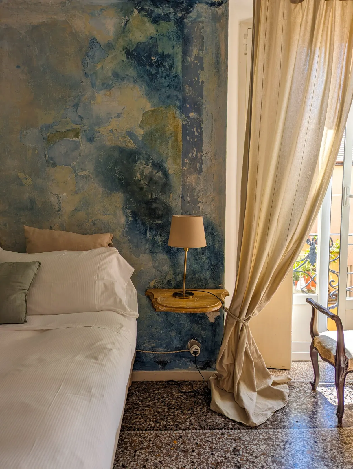 Bedroom with a blue painted wall and a white bed near the window