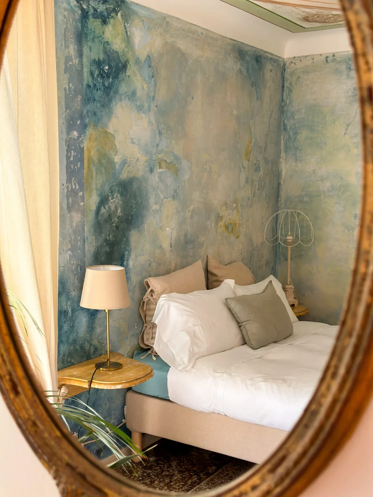 Room with frescoed walls, reflected in a gilded mirror, at a partner guesthouse