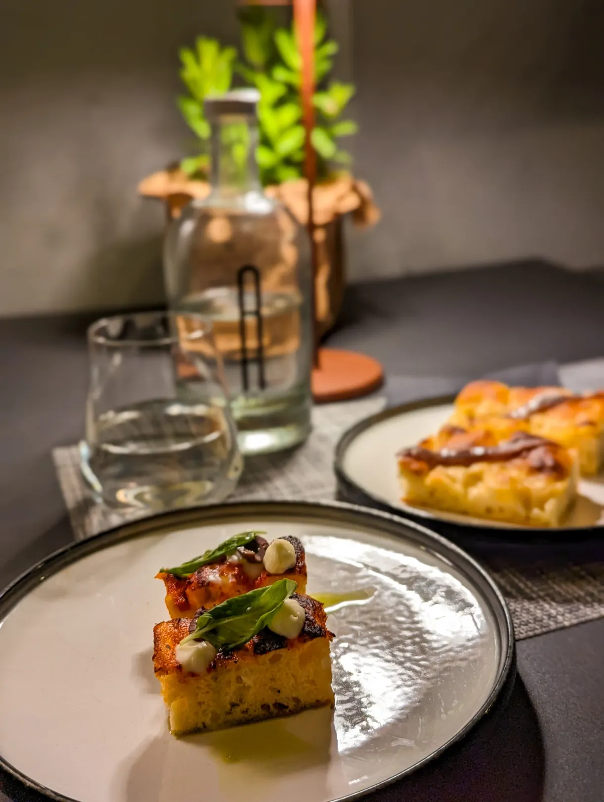 Slices of focaccia and a plated dish on a restaurant table
