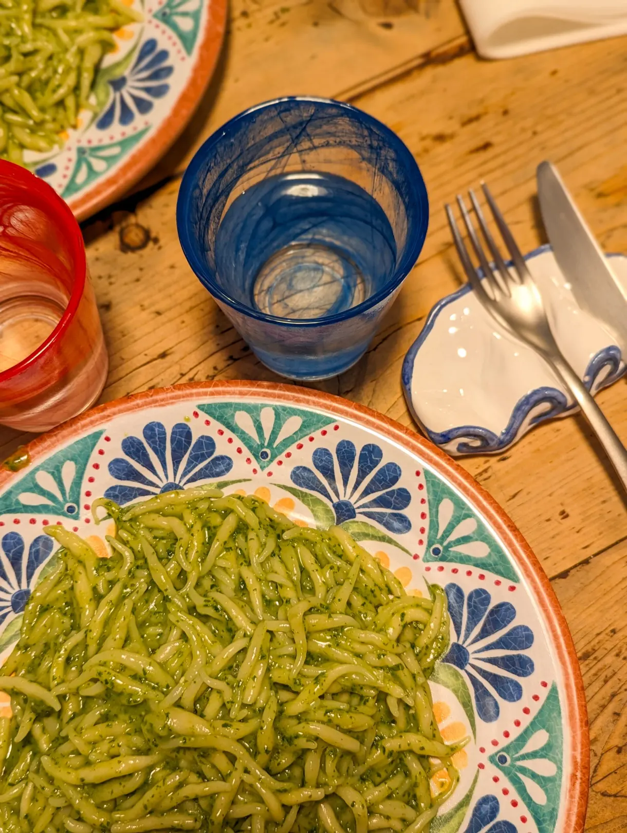 Trofie with pesto on a blue patterned plate on a wooden table
