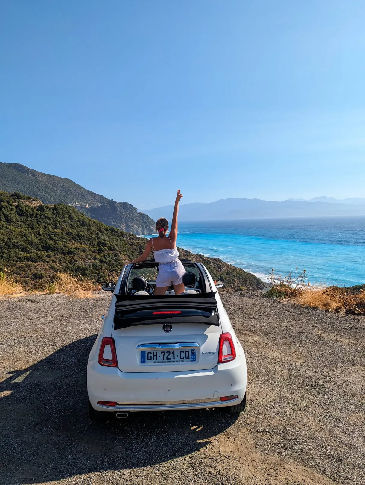 Fiat 500 décapotable garée au-dessus de la mer turquoise, sur la côte corse