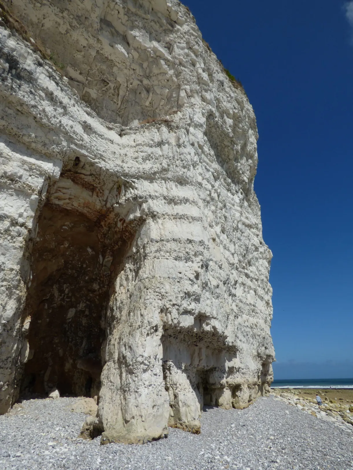 Arch carved into the white chalk at the foot of the cliff