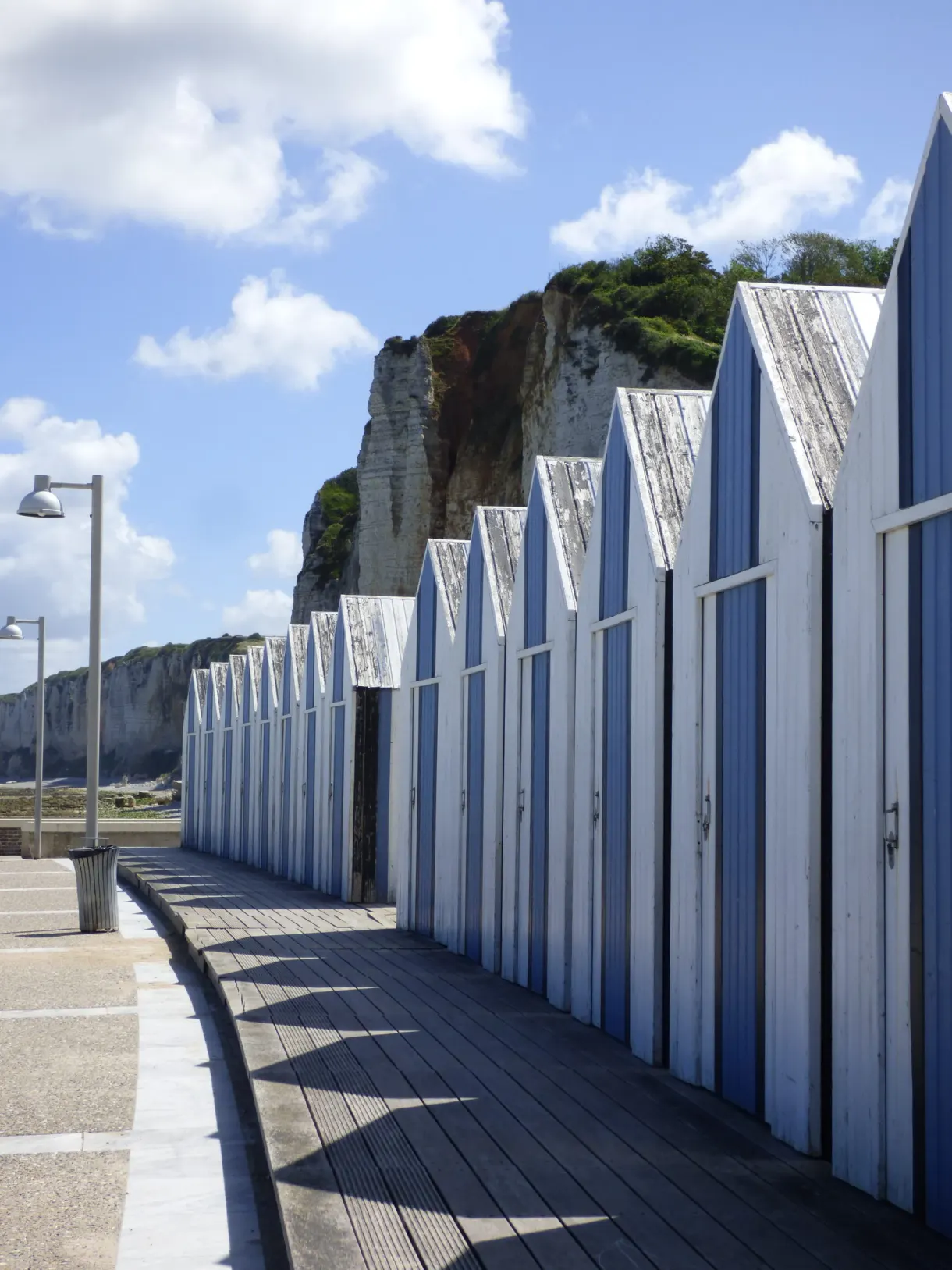 Row of white and blue beach huts beneath the cliff