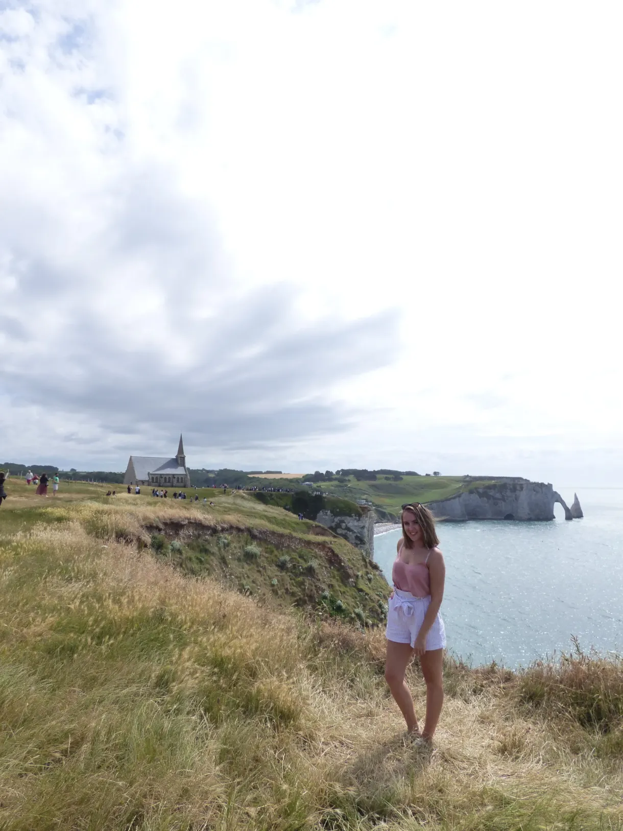 Walker on the cliff path, chapel and arch in the distance