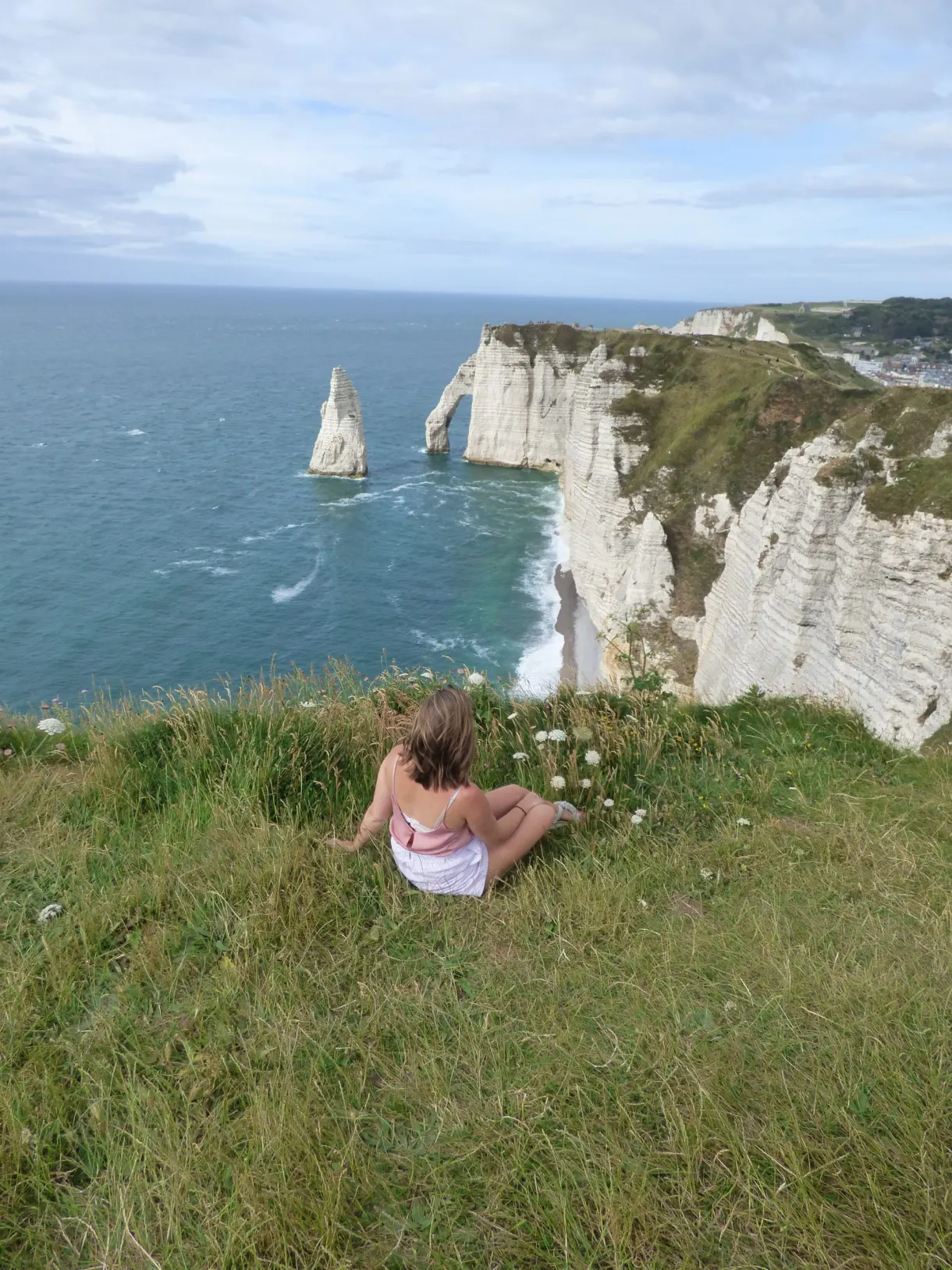 Hiker sitting in the grass facing the needle and the arch